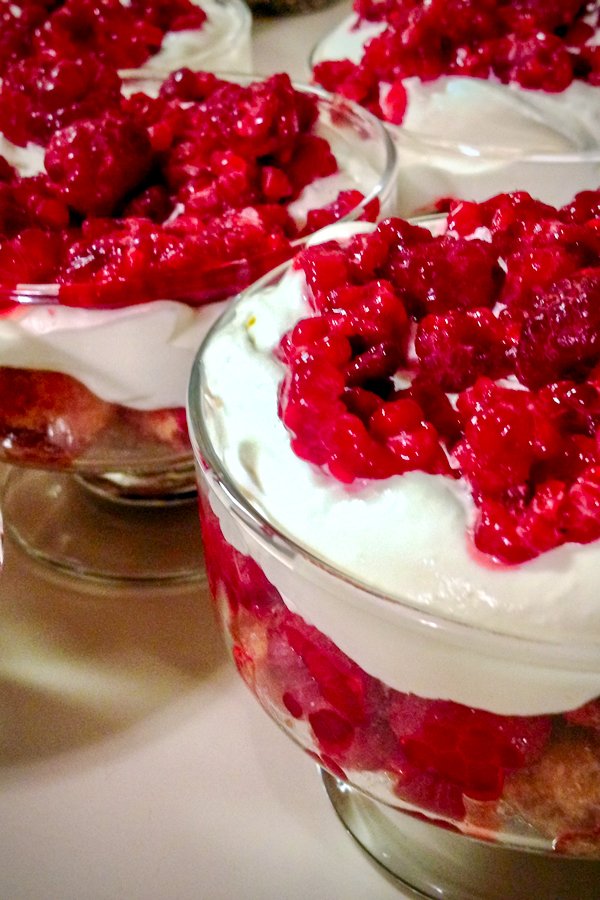 This five minutes trifles dessert can be made all year round. A wonderfully indulgent combination, sweet, creamy and with the added textures of fruit, sponge or lady fingers, it is an ideal finish to a meal. Close up of a trifle dessert with whipped cream and frozen raspberries