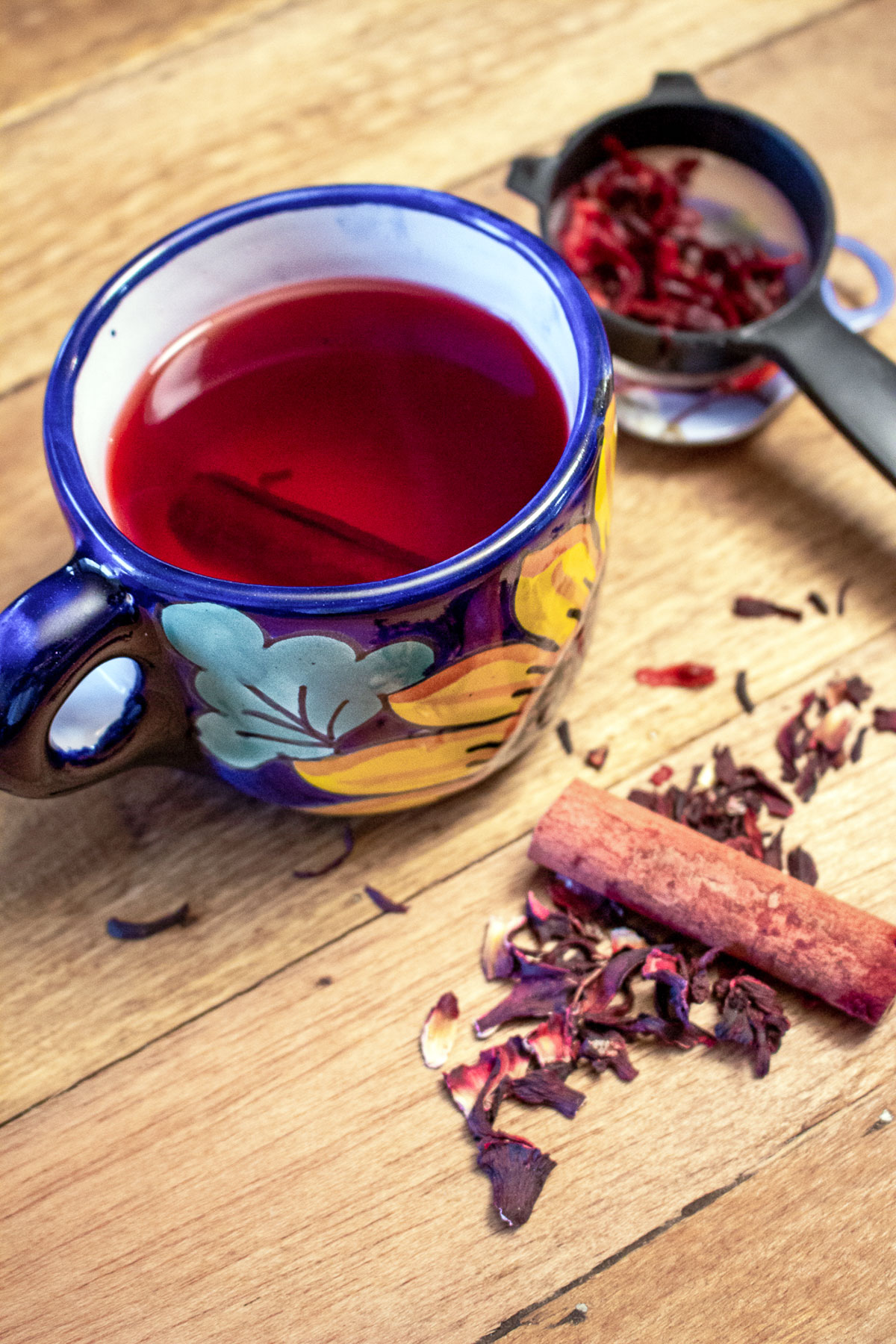 Hibiscus-Cinnamon Tea- Te de Jamaica y Canela- a popular tea that is consumed wildly in Mexico and not only, the famous Hibiscus flower tea, or Jamaica flowers te in Spanish. If you know the Mexican cuisine, you also know that this tea is called Agua De Jamaica. Hibiscus Tea with cinnamon in a mug with cinnamon sticks and dried hibiscus flowers around.