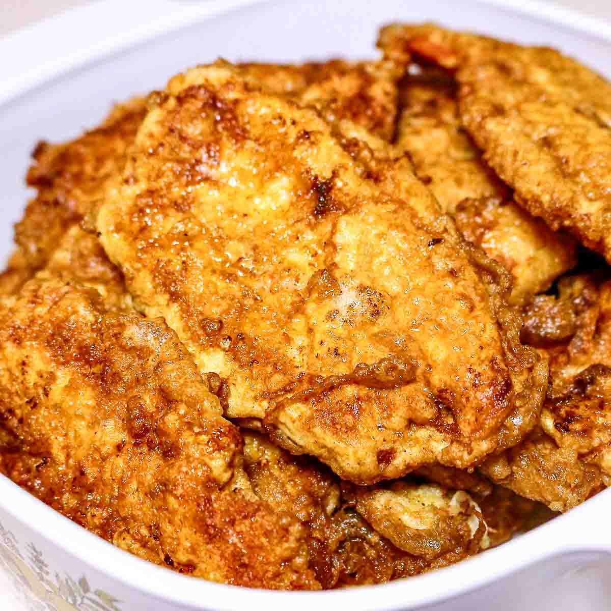Parisian Schnitzels stacked on a white serving platter.