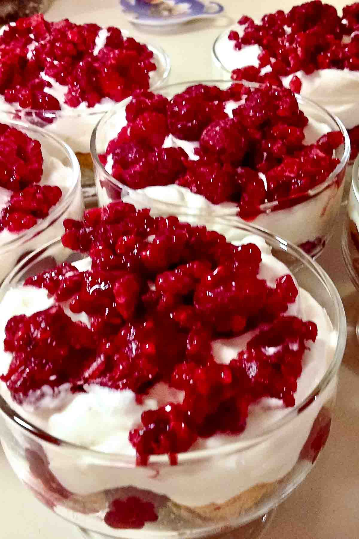 This five minutes trifles dessert can be made all year round. A wonderfully indulgent combination, sweet, creamy and with the added textures of fruit, sponge or lady fingers, it is an ideal finish to a meal. Raspberry Trifle Dessert in glass bowls.