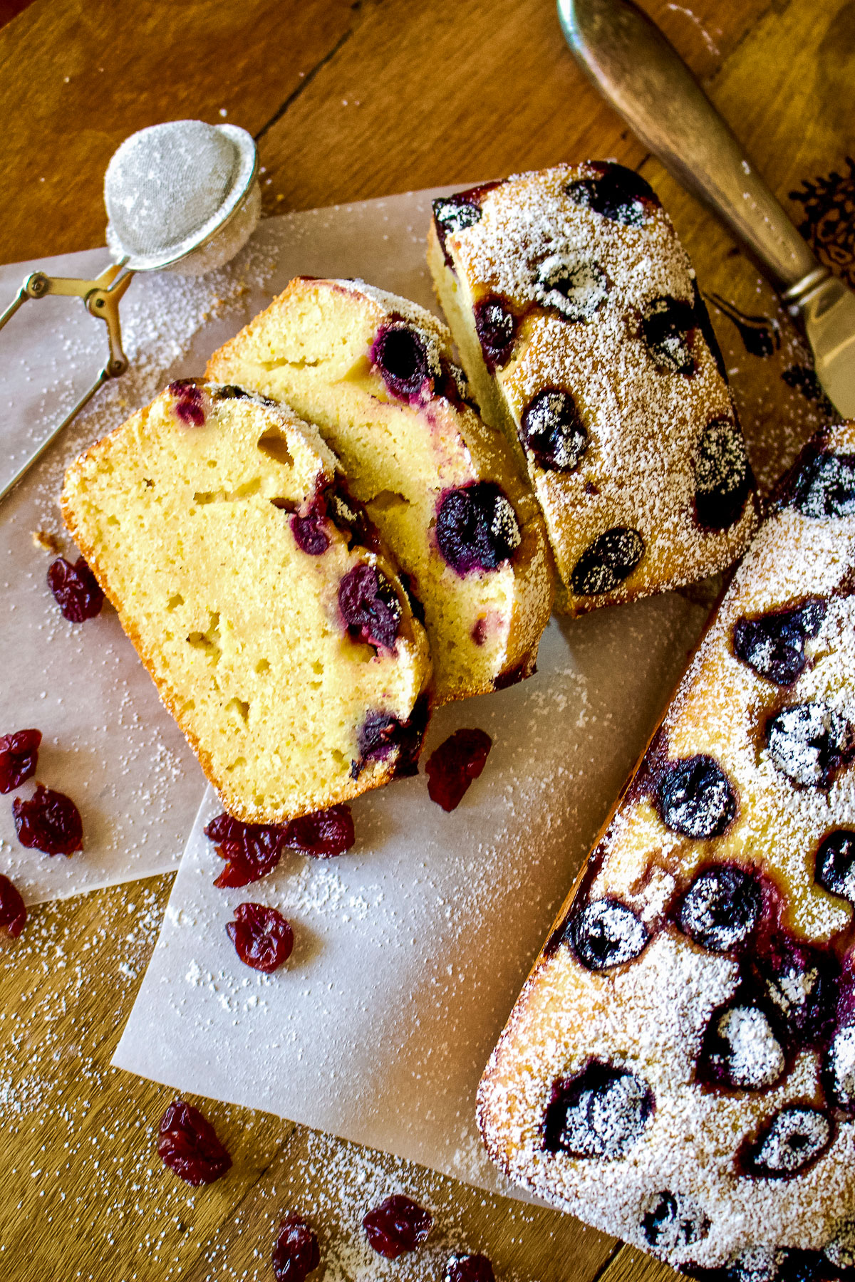 Sour Cherries Sweet Cornbread- two loaves of bread, one sliced on the left, dusted with powder sugar