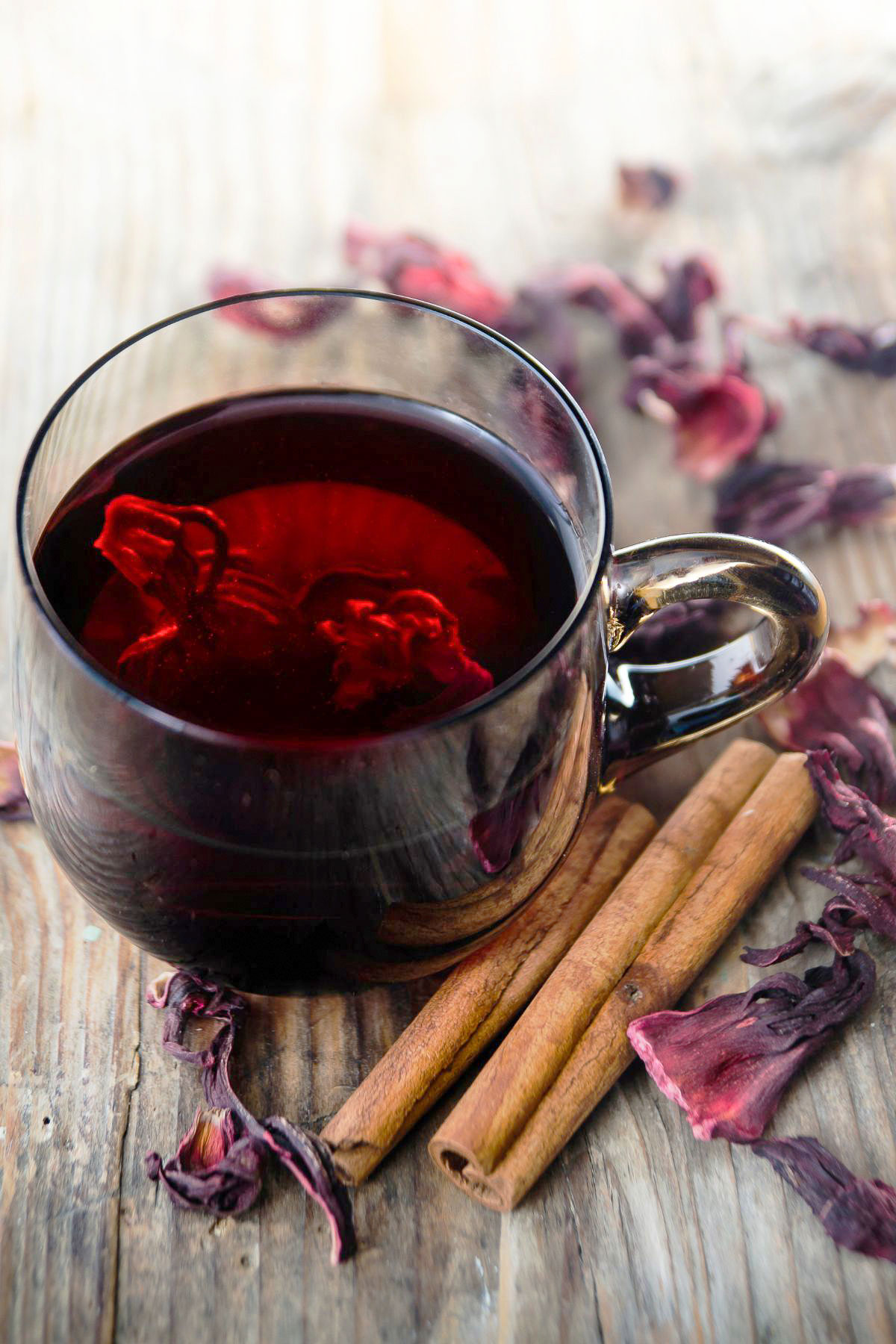 Hibiscus-Cinnamon Tea- Te de Jamaica y Canela- I am sharing with you another favorite, a popular tea that is consumed wildly in Mexico and not only, the famous Hibiscus flower tea, or Jamaica flowers te in Spanish. If you know the Mexican cuisine, you also know that this tea is called Agua De Jamaica. Hibiscus tea with cinnamon in a glass mug with cinnamon sticks and dried hibiscus flowers around.