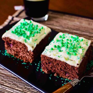 Chocolate Guinness Cake With Cream Cheese Frosting on a black platter.