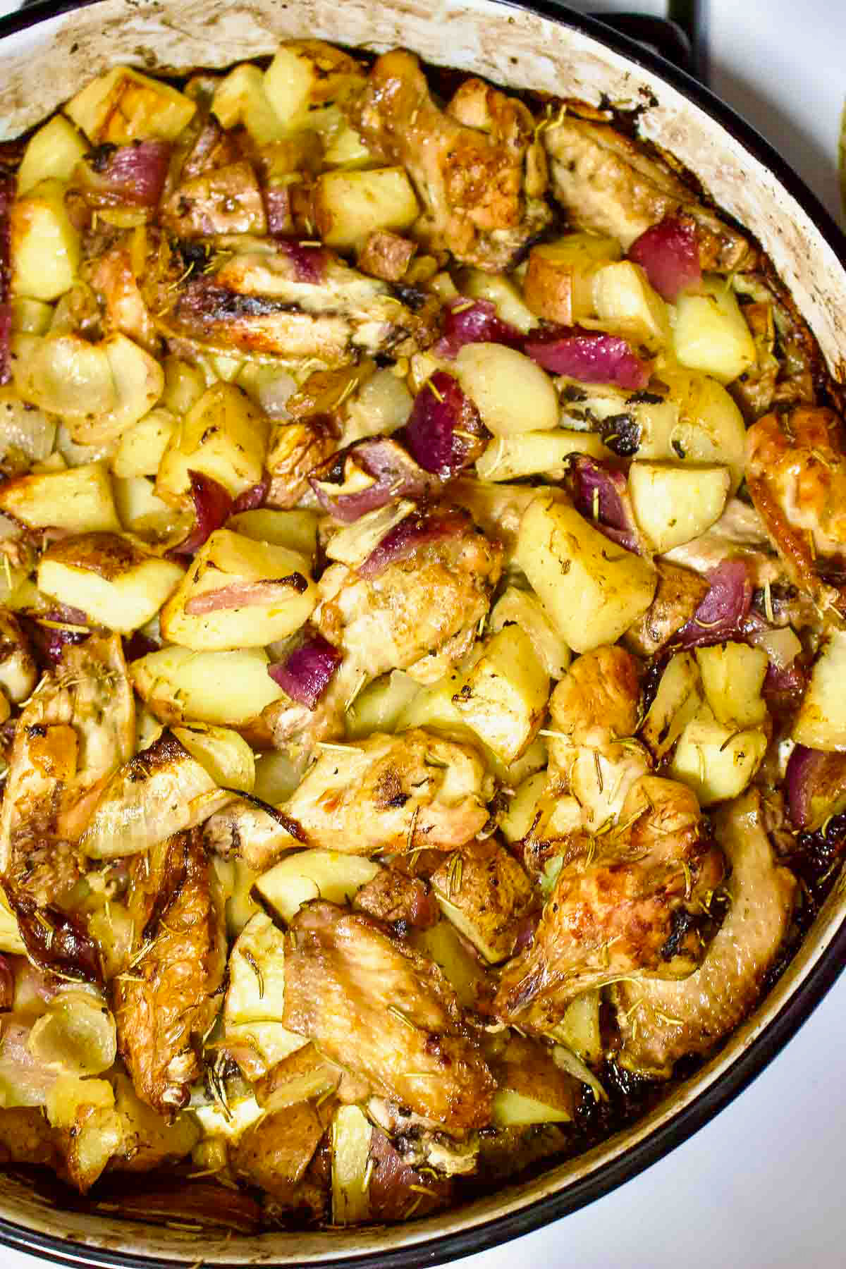 Freshly baked Sheet Pan Lemon and Rosemary Chicken and Potatoes in a round metal baking tray.