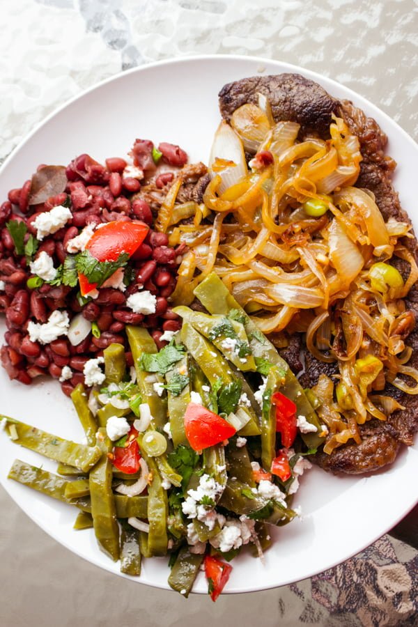 This is a basic authentic traditional Mexican beans recipe. The dish is nutritious, easy to make and so traditional that cannot miss from a respectable Mexican table. beans, steak and nopales salad on a white plate
