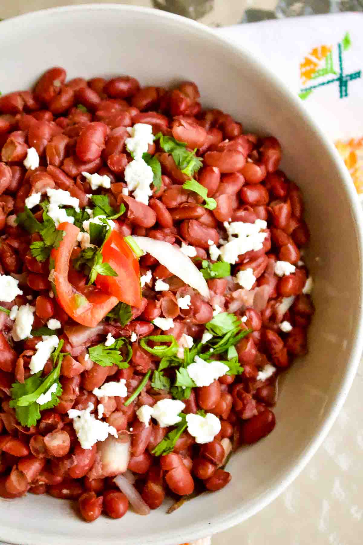 Mexican Frijoles served in a white bowl with queso fresco.