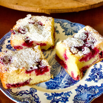 Slices of Buckle cake with berries on a white and blue plate