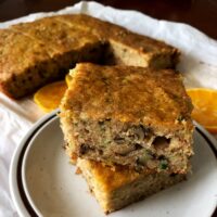Zucchini Bread With Walnuts And Orange slices on a white plate.