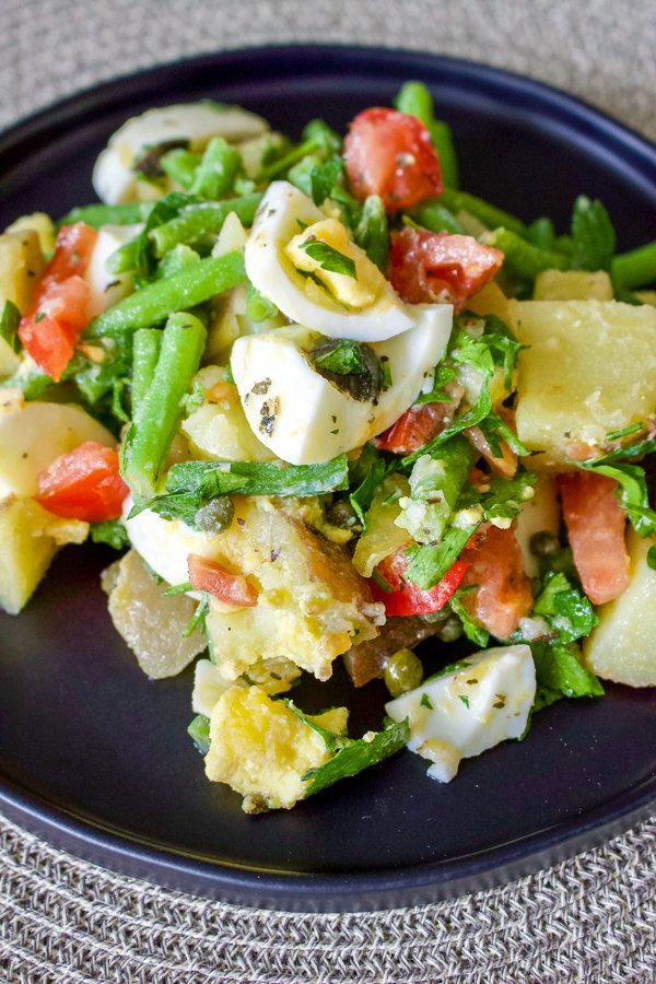 Green bean and potato salad- a delicious salad that can be served as a side dish next to your favorite cut of meat, or by itself for a light lunch or dinner. Green bean and potato salad served on a black platter