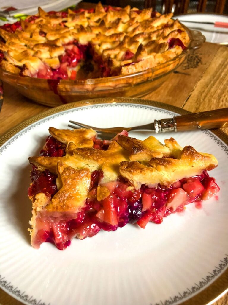 Apple And Berries Pie slice on a white plate with golden rim