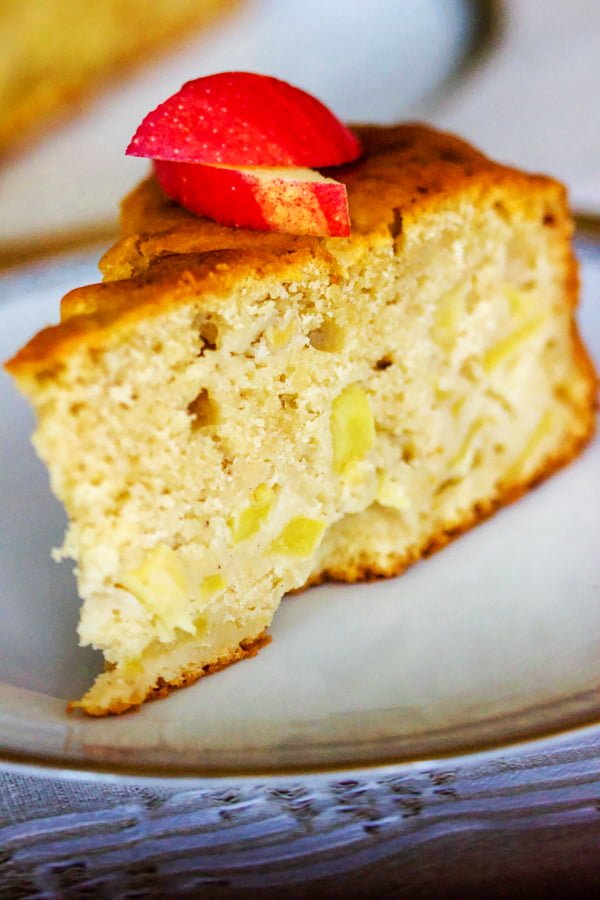 Say hello to this German Riesling Apple Cake. This is an easy, delicious cake that is made with Riesling wine and tart apples. It can also be made for any occasion, including holidays. Delicious slice of German Riesling Apple Cake on a white plate.