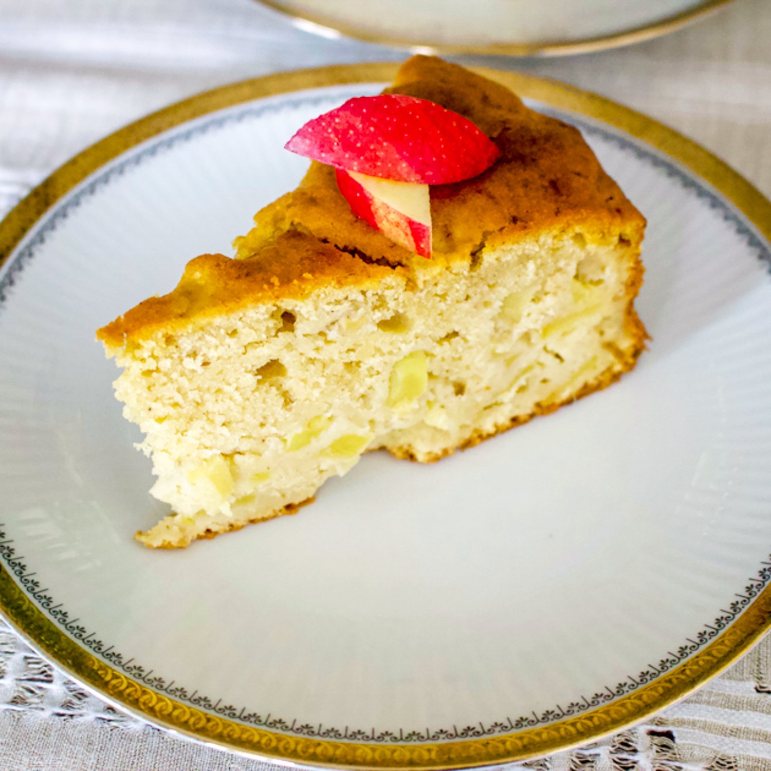 Say hello to this German Riesling Apple Cake. This is an easy, delicious cake that is made with Riesling wine and tart apples. It can also be made for any occasion, including holidays. German Riesling Apple Cake slice on a white plate