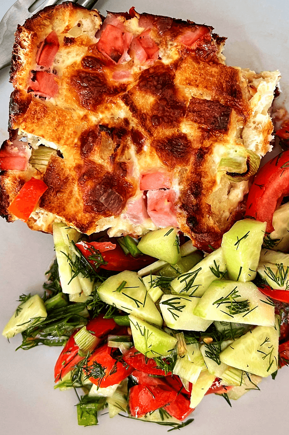 Slice of Strata with summer salad on white plate