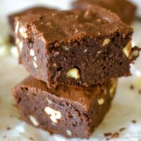 Two slices of brownies stacked on a white plate.