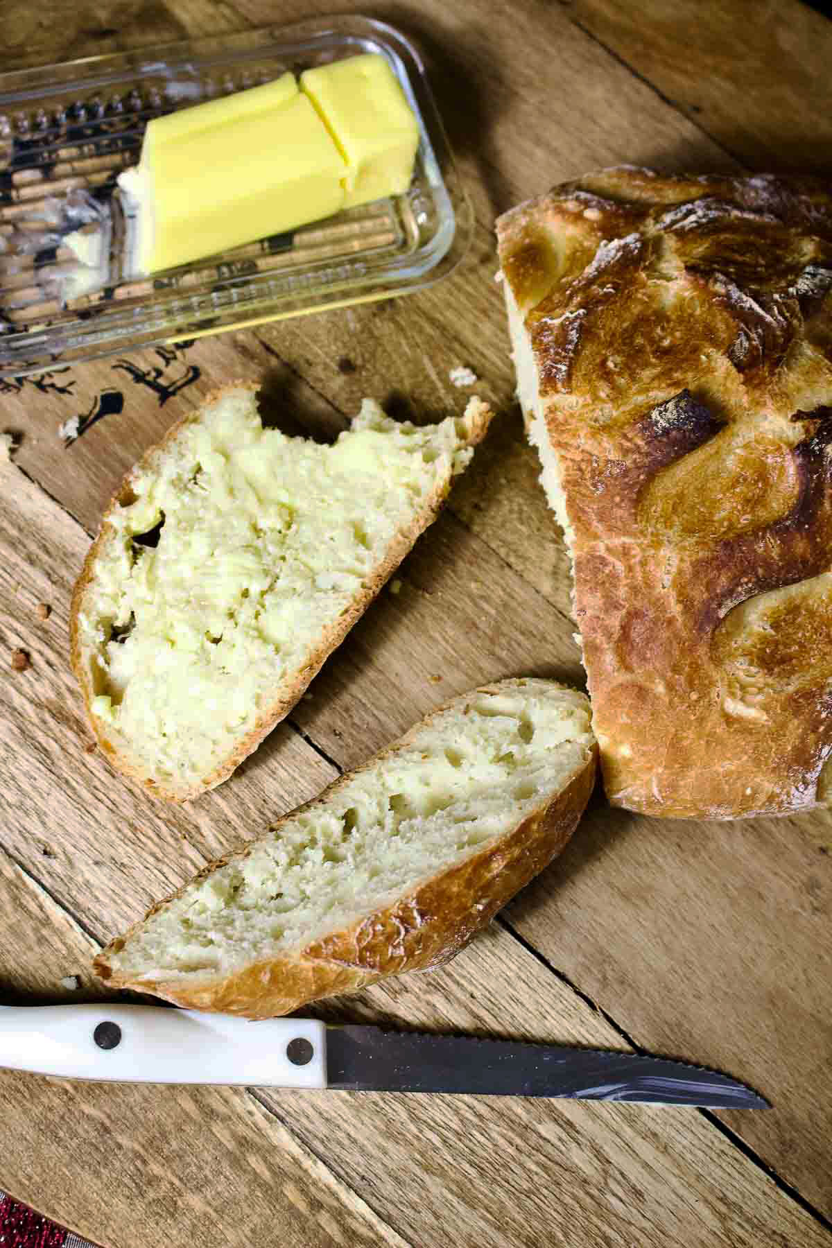 No Knead Bread sliced with butter in the background.