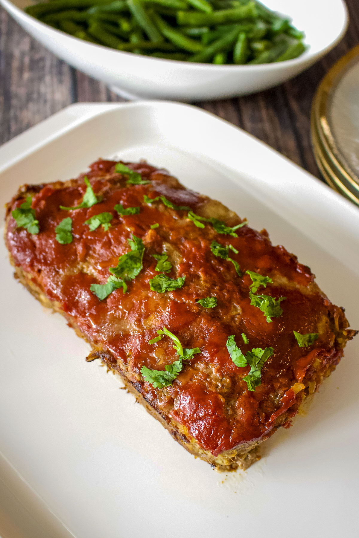Old Fashioned Meatloaf With Oats Midwest Style-on a white plate next to cooked green beans