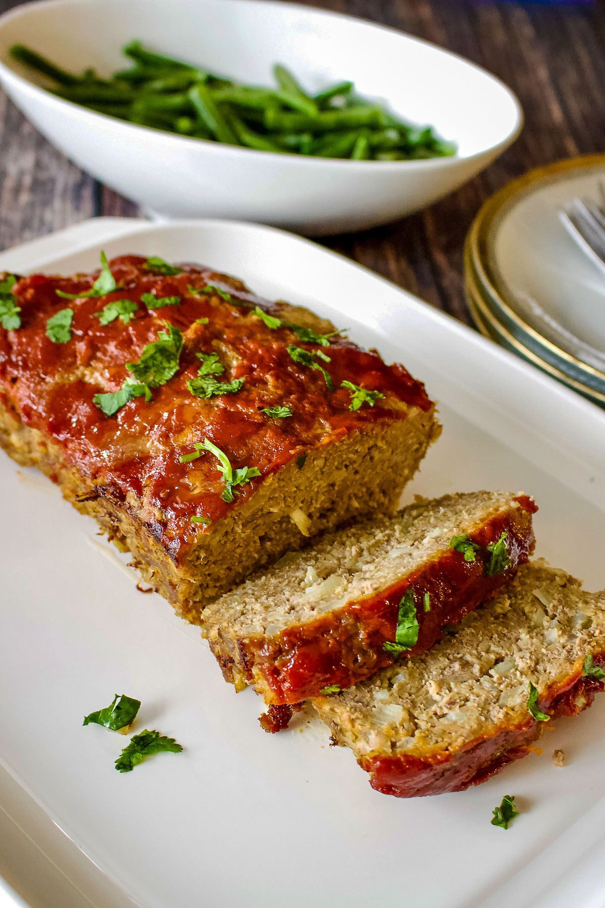 Sliced meatloaf with green beans in the background0