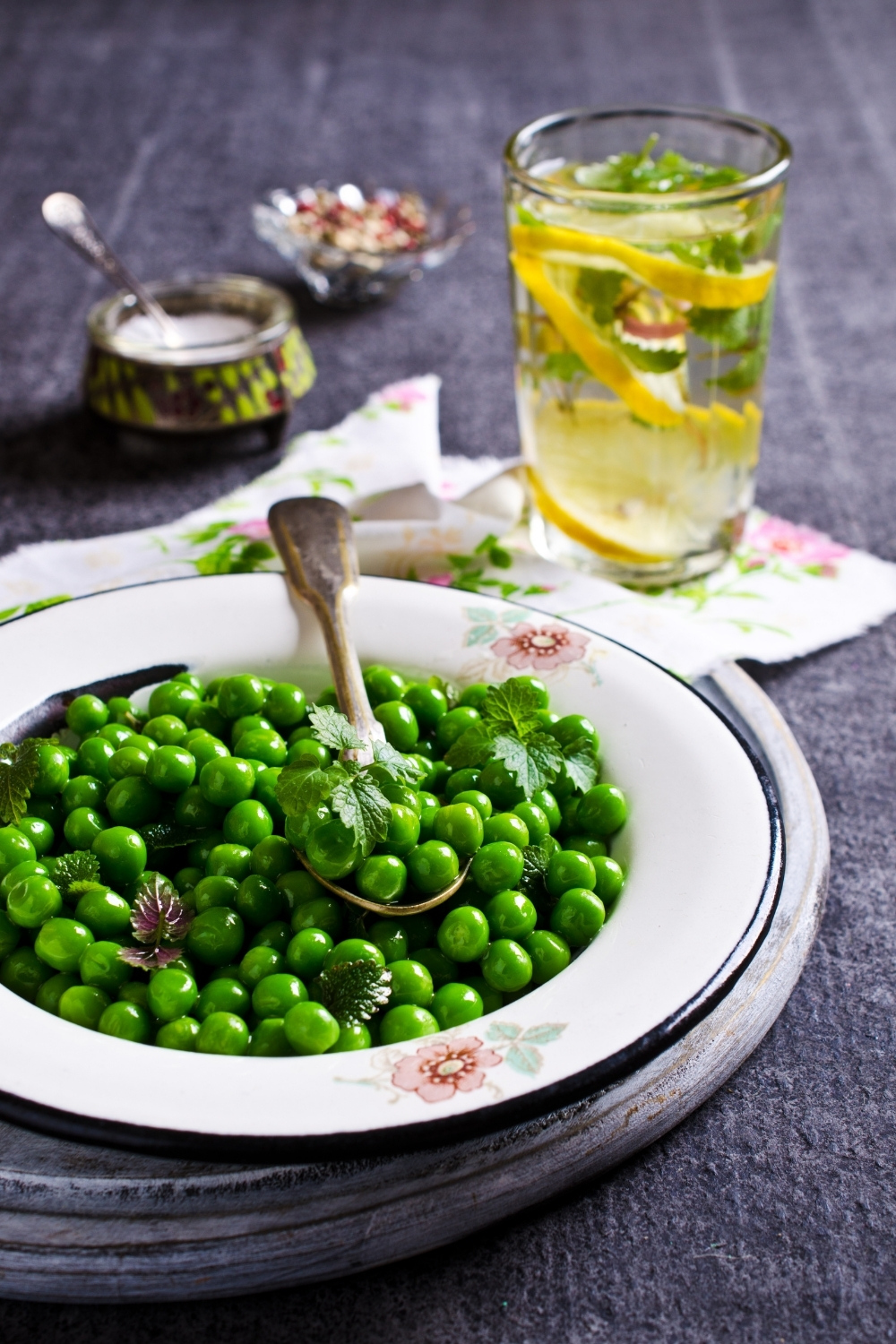 Super Easy Green Peas With Mint Recipe is an Irish recipe that combines fresh peas from the garden with fresh mint. Perfect for Spring, Easter or even a St. Patrick's Day celebration! Picture of minted peas on a white plate with spoon.