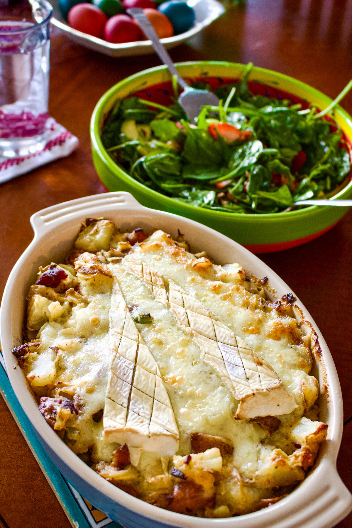 Baked Tartiflette sitting on the table with Salad behind0