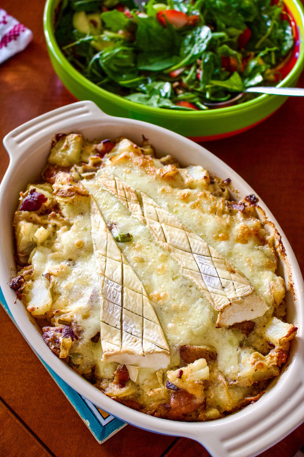 French Tartiflette sitting on the table next to a bowl of salad