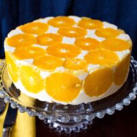 Delicious No Bake Orange Mousse Cake sitting on a glass cake support.