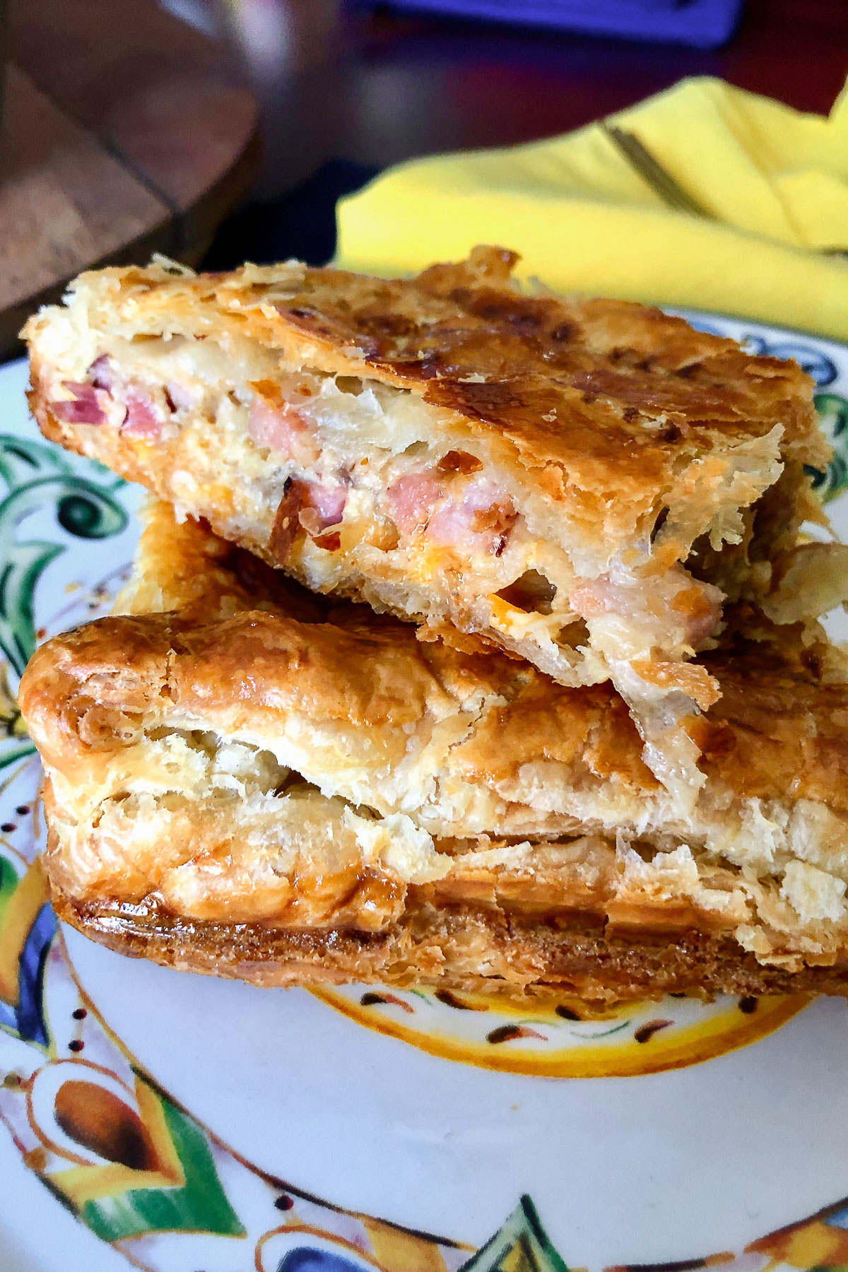 Stacked slices of caramelized onion and ham puff pastry pie close up0