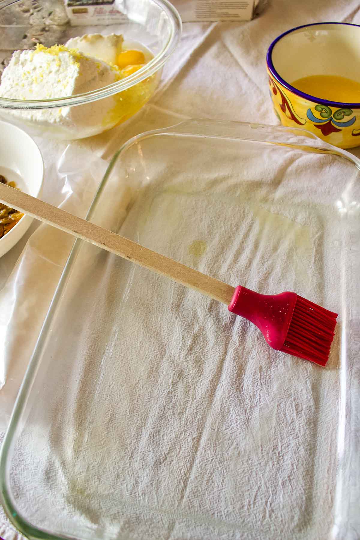 Brushing the tray with butter.