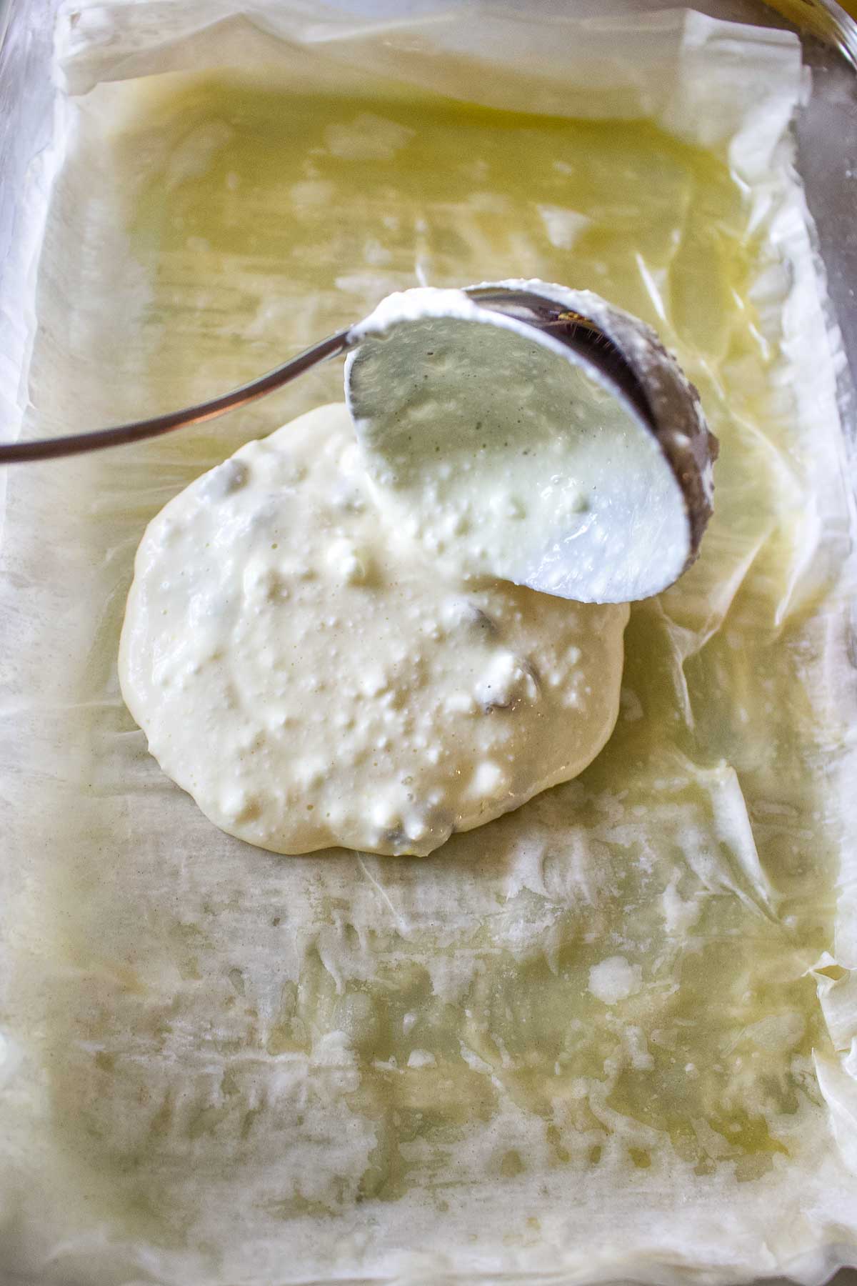 Placing layers of cheese mixture between phyllo dough.