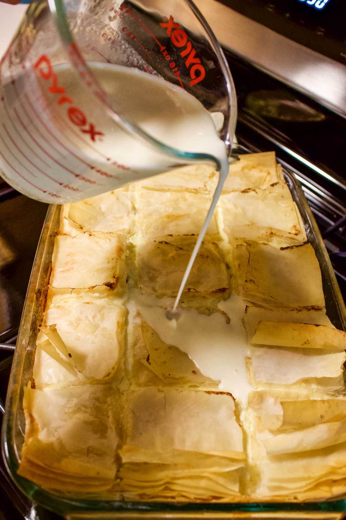 Pouring milk mixture over the pie.