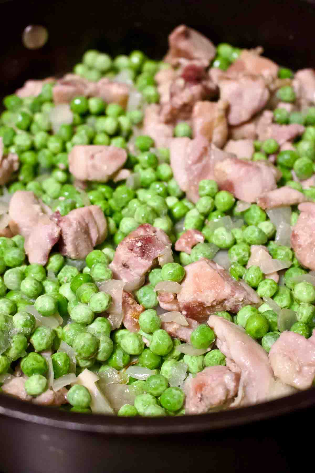 Adding green peas to the chicken.