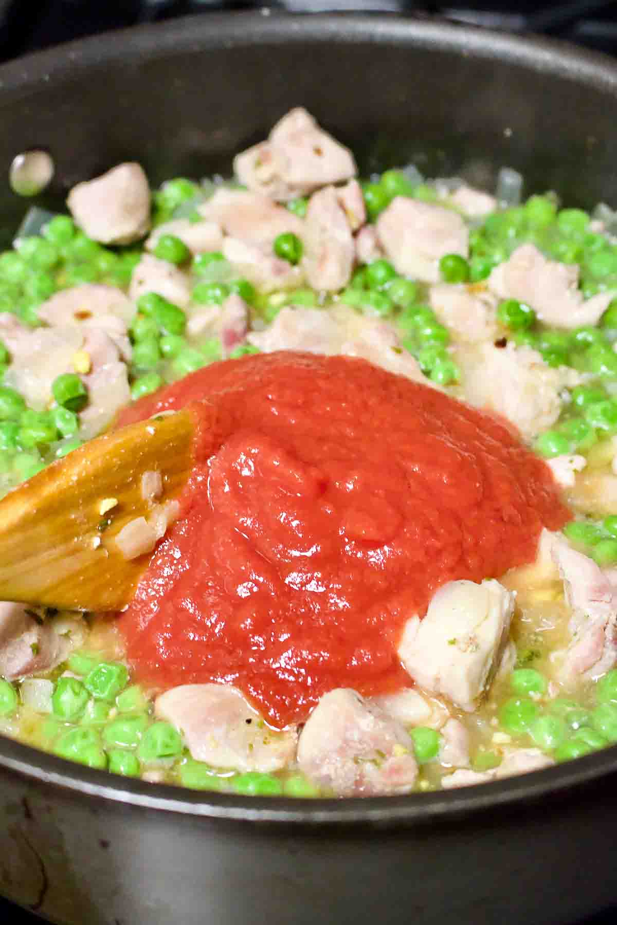 Adding tomato sauce to the green peas.