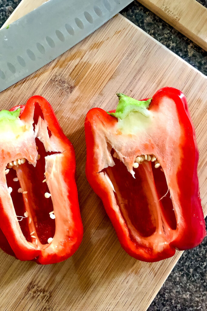 Halved red bell pepper on wooden board