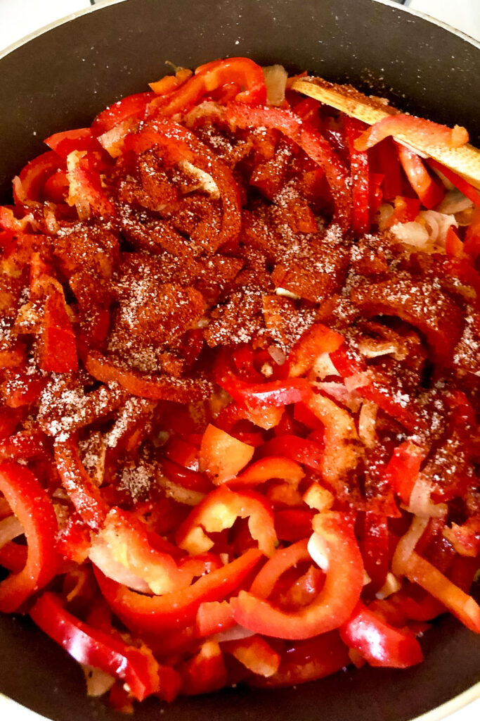 Peppers onions and garlic cooking with paprika in a pan