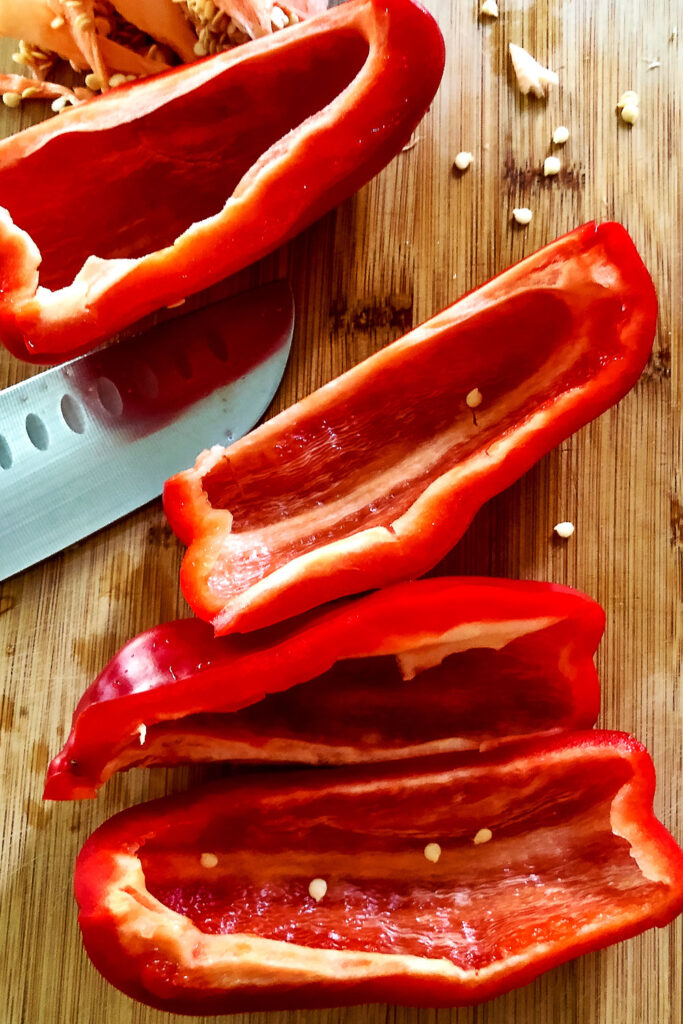 Quartered red bell pepper on wooden board