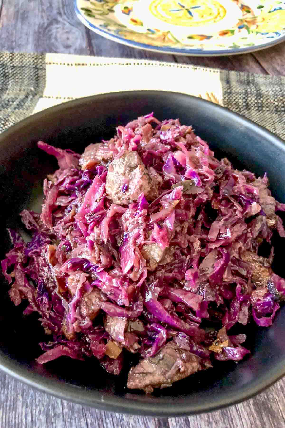 Red Cabbage With Pork served in a black bowl.