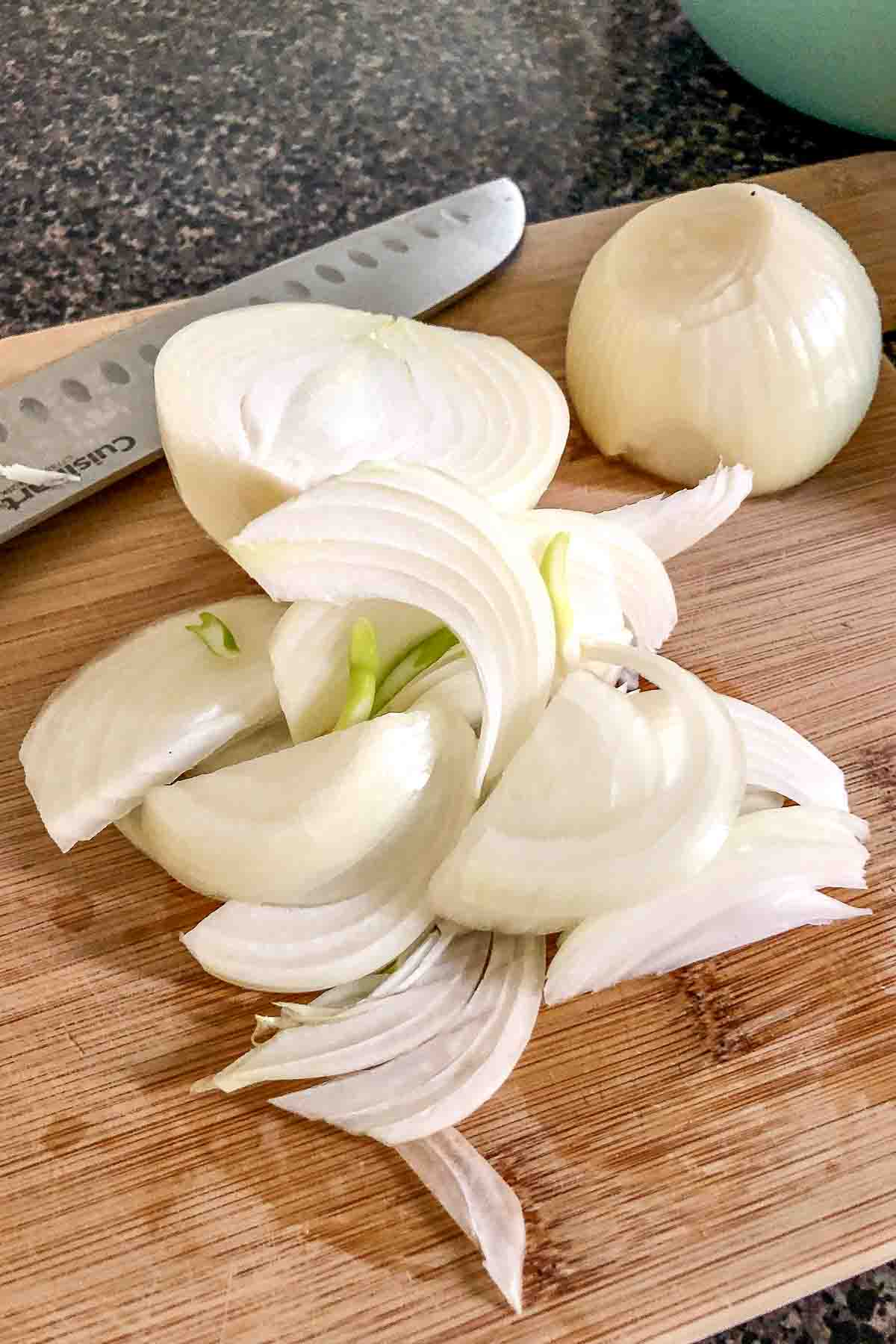 Sliced onions on a wooden board.