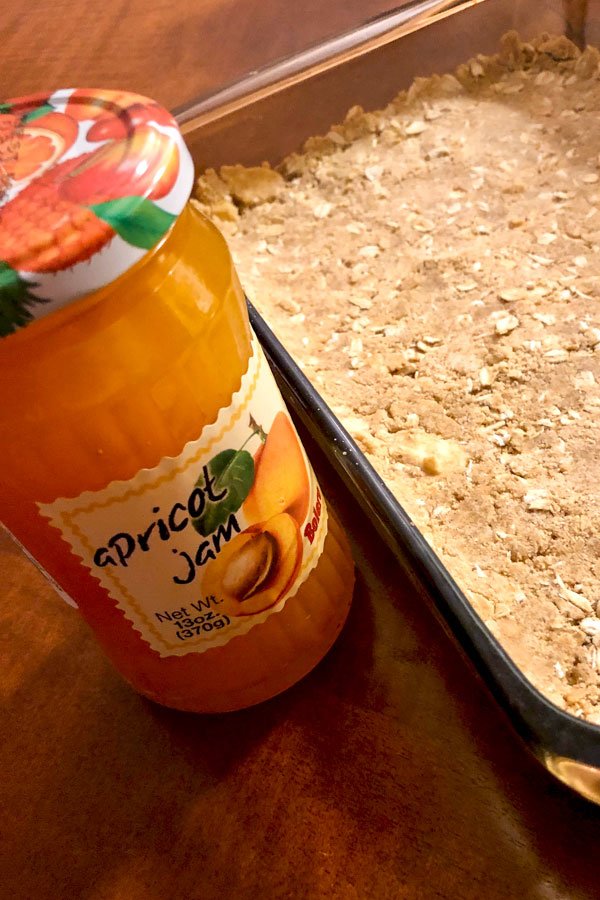 Apricot jam jar next to the crust for bars