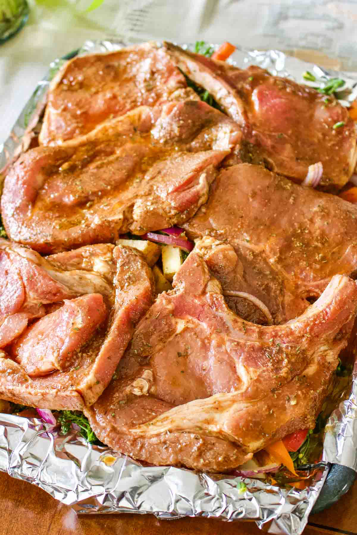 Chopped vegetables and pork chops on a baking tray.