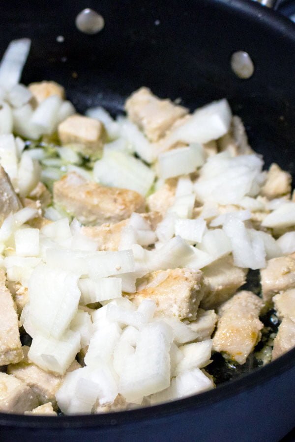 chicken breast and onions cooking in a pan