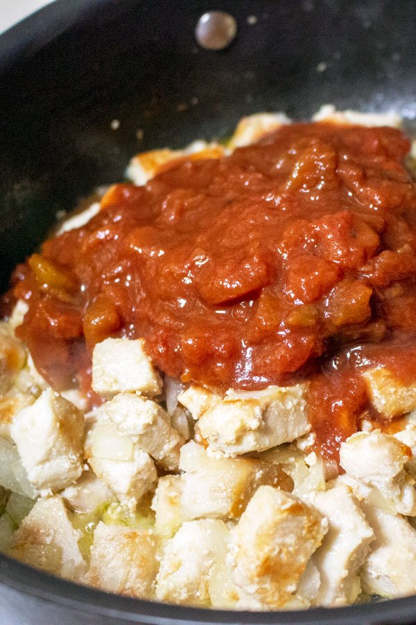 chicken breast, onions and tomatoes cooking in a pan