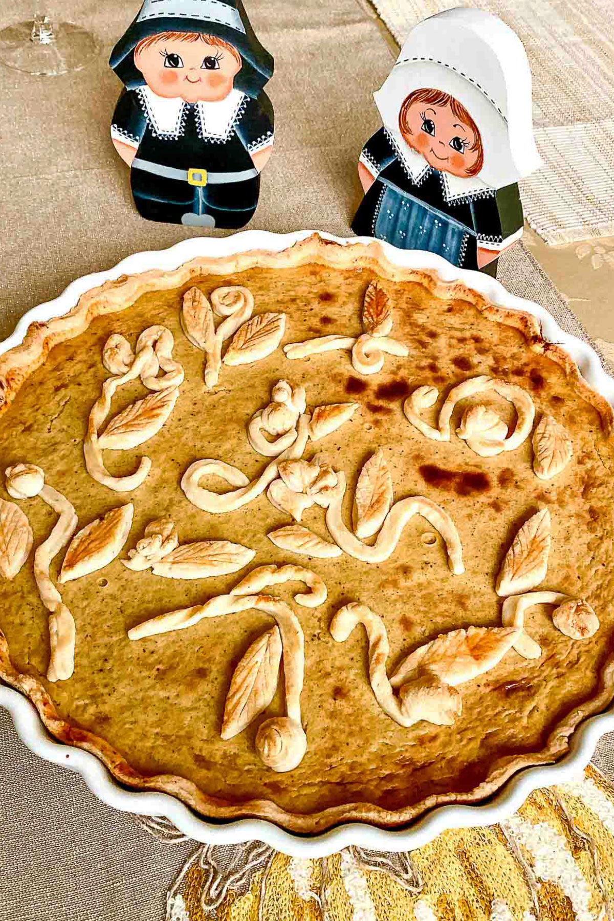 Whisky Pumpkin pie on table with Thanksgiving decorations of wooden pilgrims.