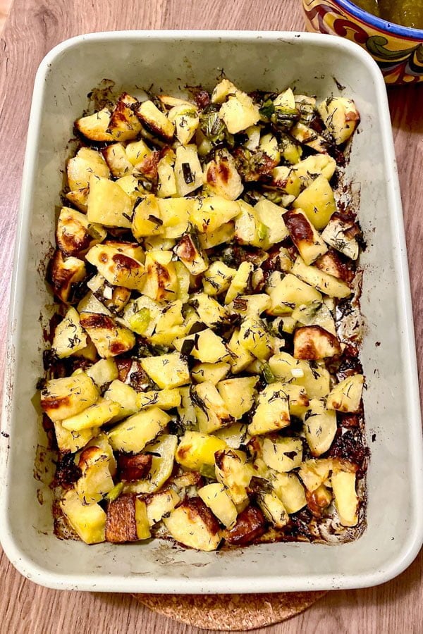 Roasted potatoes with green garlic in a white baking dish