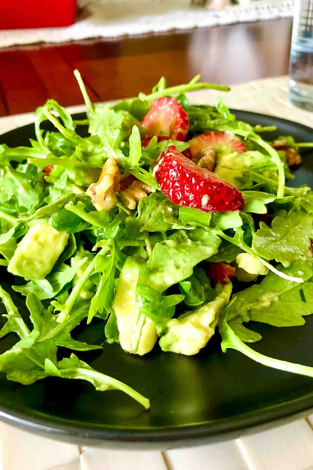 Arugula Strawberry Salad with Pecans on a black plate.
