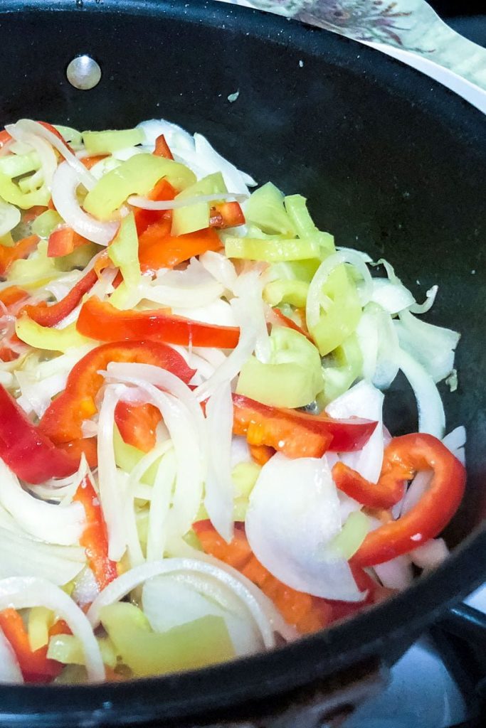 peppers and onions cooking in a pan