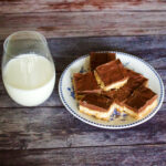 Triple Layer Chocolate Peanut Butter Cookie Bars on a plate, served with a glass of milk.