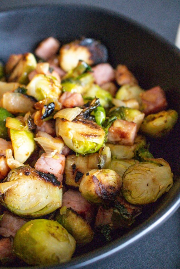 Cast Iron Brussels Sprouts With Ham-close up in a black plate