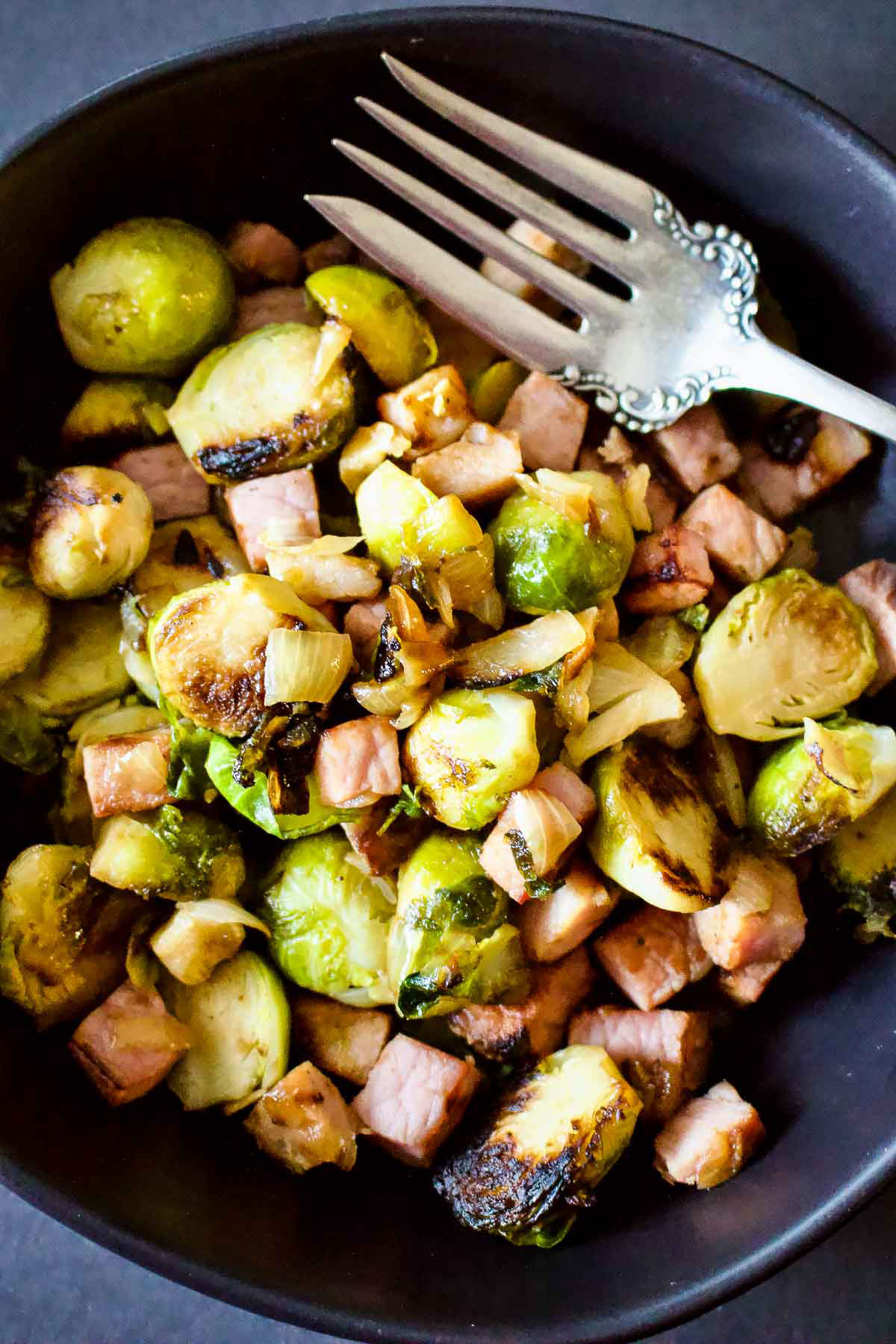 Cast Iron Caramelized Brussel Sprouts With Ham in a black bowl.