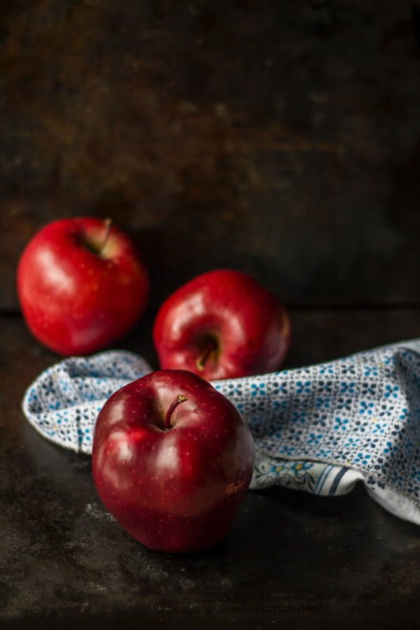 Three red apples sitting on a kitchen towel.