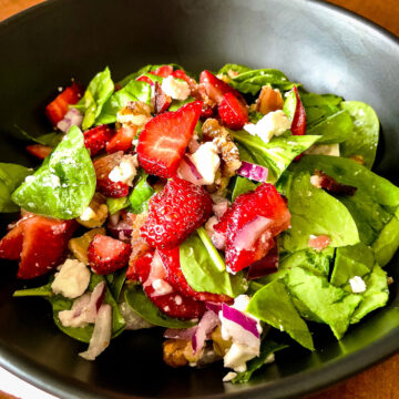 Spinach Strawberry Salad in a black serving bowl square image.