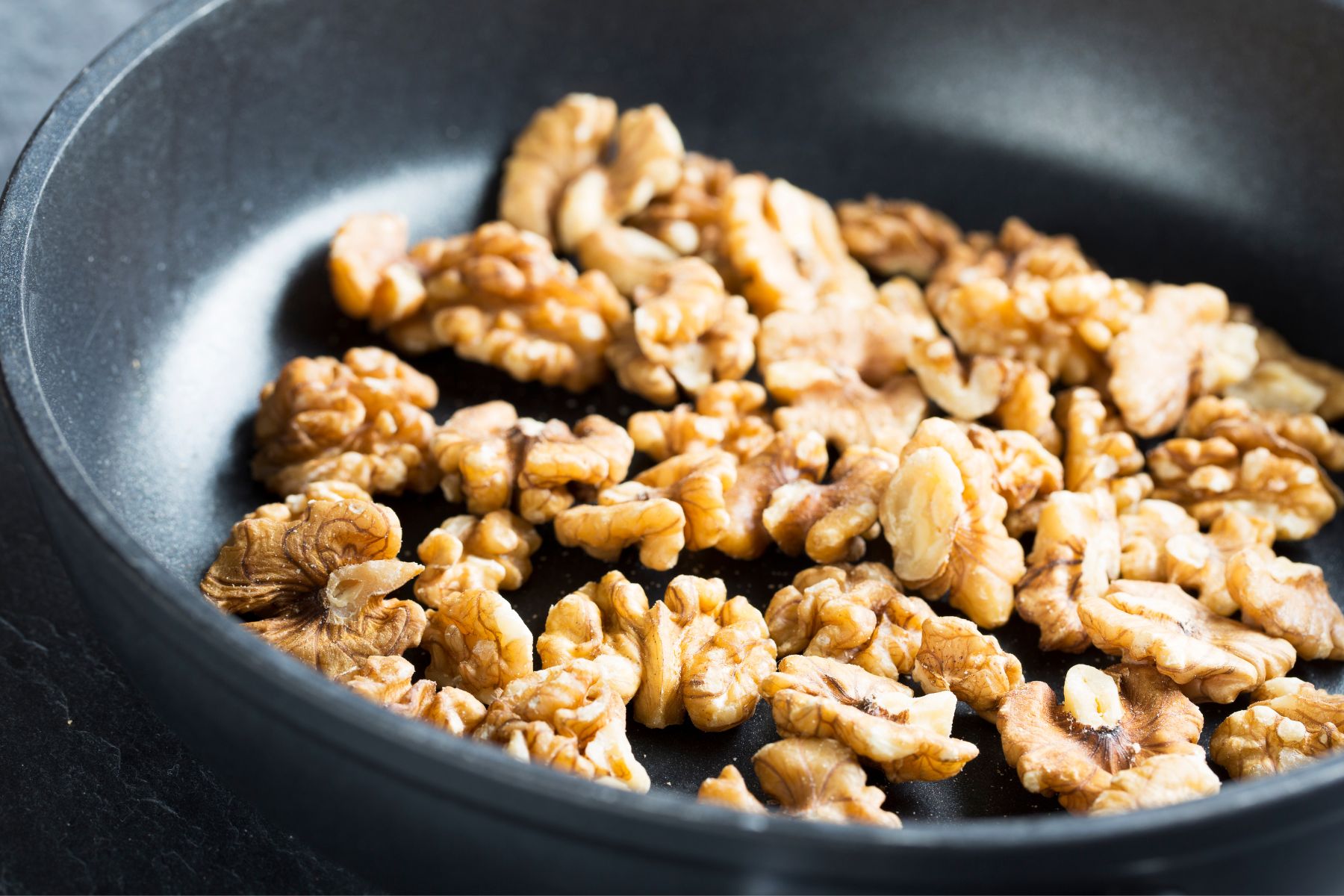 Image of walnuts toasting in a skillet.